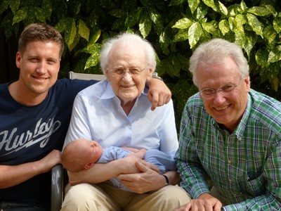 4 Generationen - Baby im Arm eines Greises umrahmt links von einem jungen Mann und rechts einem mittelalten Mann