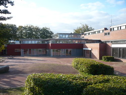 Schulgebäude bei Sonnenschein mit dem Schulhof